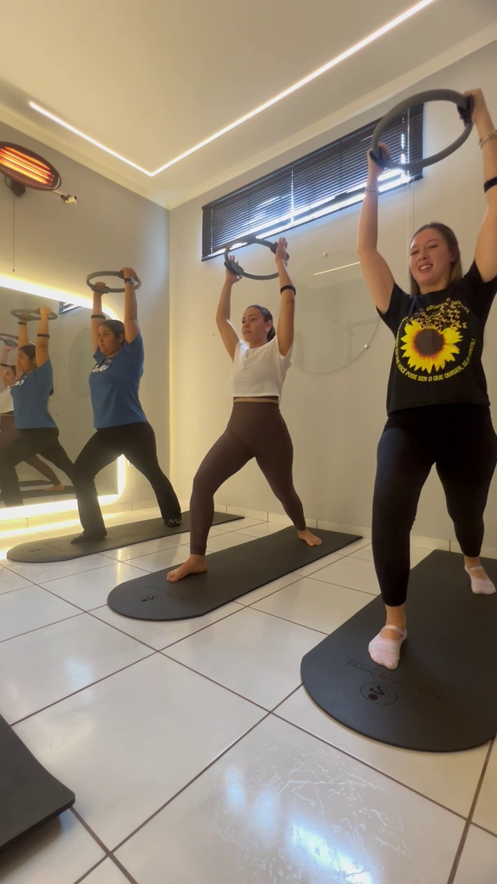 Alunas em pé durante aula de Hot Pilates com anel de Pilates