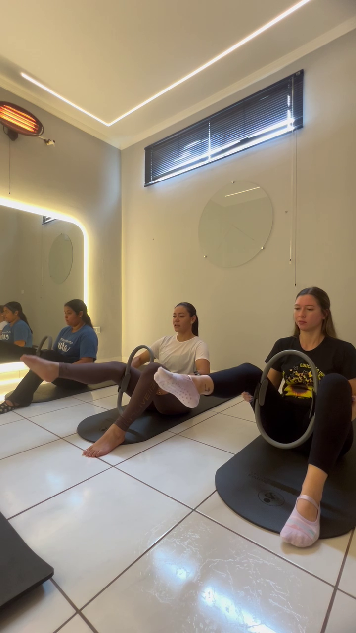 Alunas em exercício de Hot Pilates no solo com anel de resistência